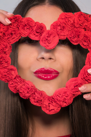 Portrait of a sweet perfect girl smiling at camera with heart shaped paper in her hands. Valentine's Day or Women's Day concept.の写真素材