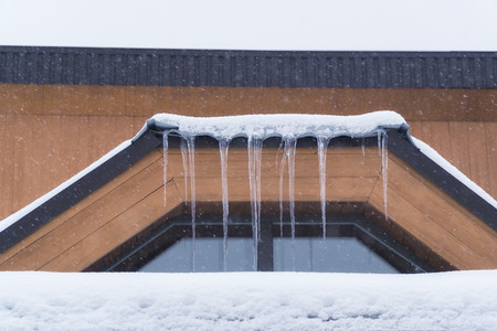 Wintry roof of the house with icicles on sky background.の写真素材