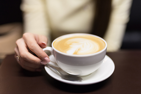 A girl is drinking coffee in a cafe. Small depth of field.の写真素材