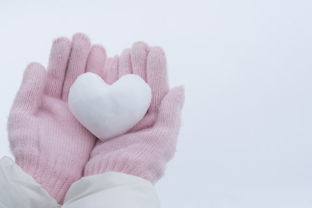 Hands in pink gloves holding snow heart.の写真素材