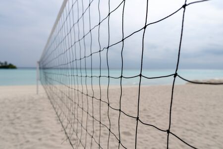 view from a volleyball net at the beach to a tropical island in the turquoise seaの写真素材