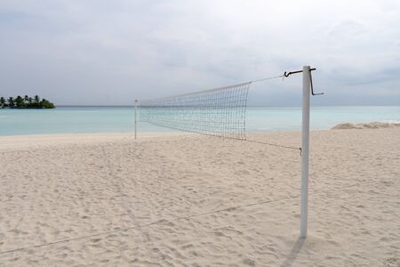 view from a volleyball net at the beach to a tropical island in the turquoise seaの写真素材