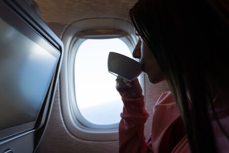 Young woman drinking a coffee in airplaneの写真素材