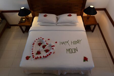 Creamy pillow and heart form, valentine signature made from red rose flower on bed decorationの写真素材