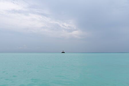 The guy is standing on a rock in the middle of the ocean and waving his arms. A person needs help
