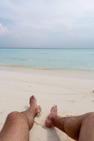 Relax on the beach. In the frame of the guys feet.の写真素材