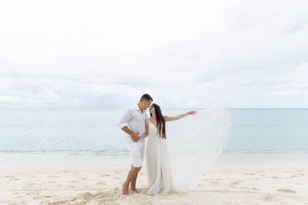 Newlyweds are hugging on a gorgeous beach with white sand and turquoise water.の写真素材