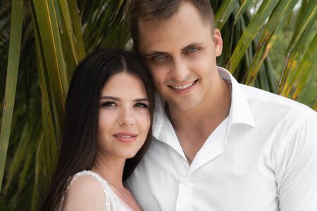 Happy married couple. Newlyweds stand under the leaves of palm trees.の写真素材