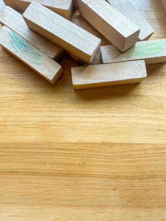 Pile of blocks from wooden blocks tower stacking game scattered on a wooden surface. Textured wooden background with copy spaceの写真素材