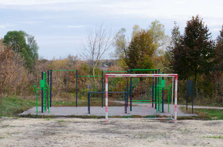 An outdoor sports ground with green and black metal equipment and part of soccer field with football...