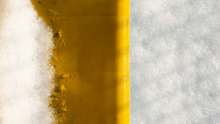 Horizontal banner. Melting snow on orange plastic surface on bright sunny day background.