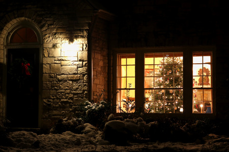 A brightly decorated Christmas tree in a window at December night before Christmas.Holiday Christmas and New Year background with welcome home christmas tree in the window at night.の写真素材