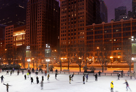 People in motion enjoying ice skating during beautiful winter night in Chicago downtown. Urban architecture background, big city life concept.のeditorial素材