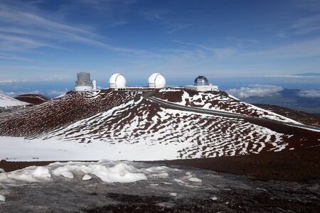 Hawaii Big Island nature background. Scenic view from mountain with paved road between observatories, snow remains and bright blue sky.の写真素材