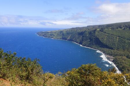 Amazing Waipio Valley landscape with volcanic origin cliff in the bright blue Pacific ocean water with black sand beach.の写真素材
