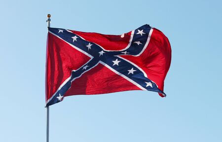 Confederate rebel flag waving in the wind against the blue sky background in Charleston, South Carolina, USA.の写真素材