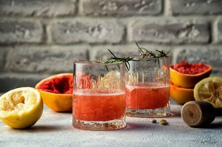 Close up. Two glass glasses filled with red drink. Around them are multicolored squeezed citrus halves and mortar. Copy space. Brick wall background.の写真素材