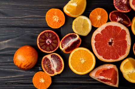 Top view, flat lay, macro. An abundance of sliced colorful citrus fruits. Dark wooden background.の写真素材