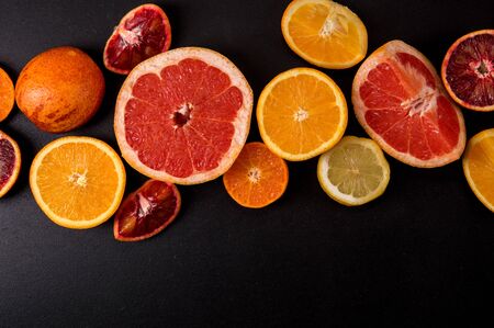 Top view, flat lay. Sliced bright citrus on a black background. Copy space.の写真素材