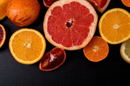Top view, flat lay, macro. Sliced bright citrus fruits on a black background.の写真素材