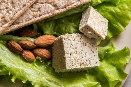 Close up, macro. Flat lay. Diet vegan food. Midday snack consisting of green lettuce, almond, tofu,...