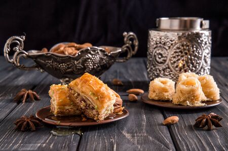 Close up, macro. Still life. Eastern honey sweets. Turkish traditional baklava with pistachios and baklava bird's nest. Dark wooden background.の写真素材