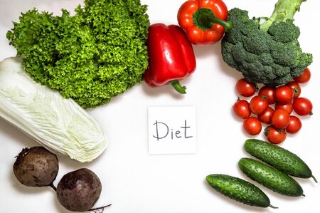 Close up, flat lay. The inscription Diet, surrounded by fresh vegetables, white background. Concept.の写真素材