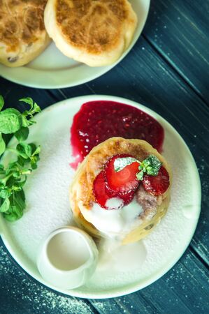 Top view. Close up, macro. Rustic breakfast. Cheese pancakes, poured with cream and decorated with strawberries. Wooden background.の写真素材
