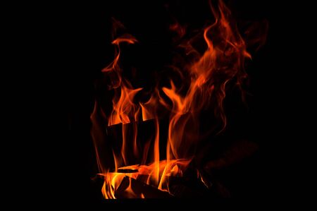 Close up, macro. Abstrack background. Burning wood in the fireplace. Red-orange flames meander in the darkness. Copy space.の写真素材