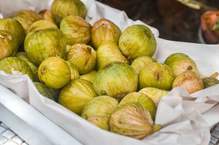 Close up, macro. Figs fruit. Yellow ripe juicy fruits sold in a box.