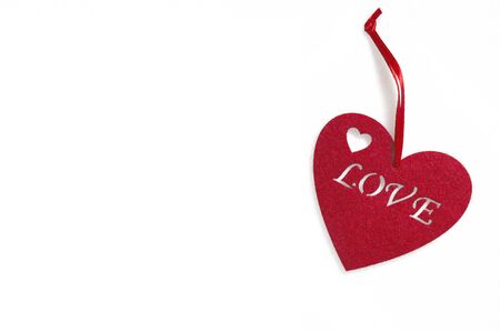 Close up, macro. Greeting Card on Valentine's Day. Red felt heart with an inscription love. Object are located on the right, isolated on white background. Copy space.の写真素材