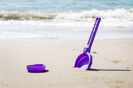 Children's mold and scapula on the seashore. Azure sea waves against the background.の写真素材