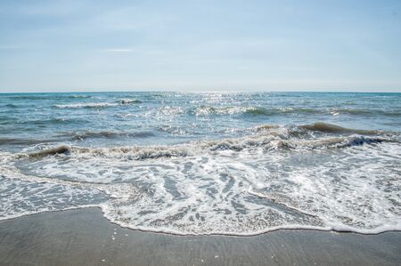 Close up. Italy, Rome, Ostia. Coast of the Tyrrhenian Sea. Seascape. A fine day, blue sky, foamy waves of the azure sea roll to the sandy shore. Copy space.の写真素材