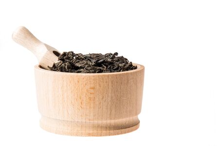 Close up, macro. Profile of wooden bowl with large leaf dried black tea. Isolated on white background. Inside placed measuring spoon. Copy space.の写真素材
