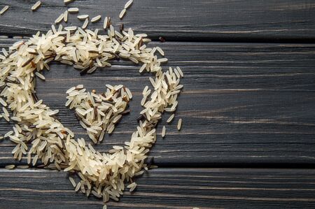 Macro, close up. Ingredients. Heart shaped hill of wild rice on a dark wooden background. Asian cuisine.の写真素材