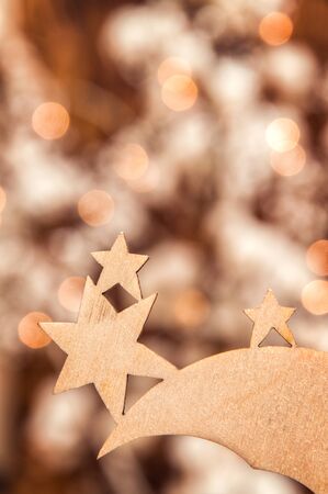 Christmas theme, card. Close up. Three-star Christmas wooden toy. Blurry lights of garland on the background. Copy space.の写真素材