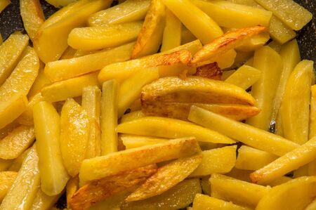 Close up. Fried potatoes. Slices of chopped potatoes are fried in vegetable oil.の写真素材