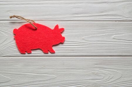 Macro, flat lay. Symbol of the Chinese New Year 2019. White wooden background. On the left, a pink pig cut out of felt ornament. Copy space on the right.の写真素材