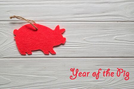 Macro, flat lay. Symbol of the Chinese New Year 2019. White wooden background. On the left, a pink pig cut out of felt ornament. Inscription on the right: Year of the Pig.の写真素材