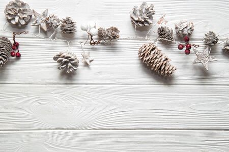 Top view, flat lay. Christmas woden background. Traditional garland with red berries, snowy fir cones and stars. Copy space below.の写真素材