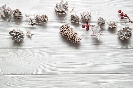 Top view, flat lay. Christmas white background. Rustic garland with fir cones, red berries and snowy stars. Copy space below.の写真素材