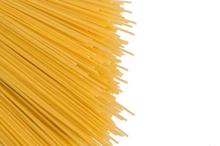 Close up, macro. Top view, flat lay. Raw yellow spaghetti isolated on white background. Spaghetti laid out diagonally. Copy space on the right.の写真素材