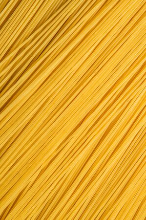 Close up. Top view, flat lay. Raw yellow spaghetti laid out diagonally. Texture.の写真素材