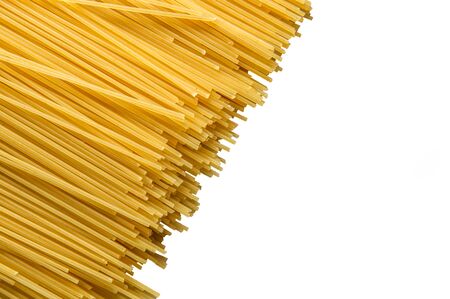 Close up, macro. Top view, flat lay. Raw yellow long spaghetti isolated on white background. Spaghetti laid out diagonally. Copy space.の写真素材