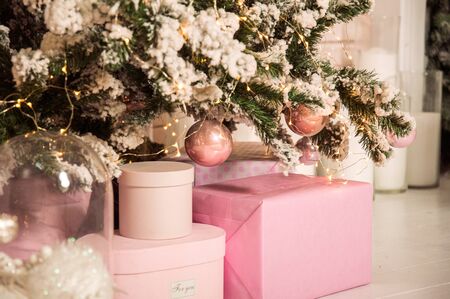Close up. Beautiful pink gift boxes near a decorated Christmas tree. Christmas concept. New Year's tradition. Copy space.の写真素材