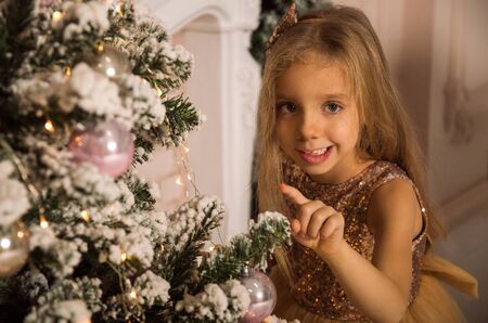 Close up, macro. Portrait of a fun smilling little girl near by Christmas tree. Christmas concept.の写真素材