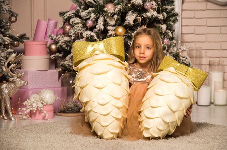 Close up. Christmas concept. A little girl is surrounded by large decorative cones near the festive Christmas tree.の写真素材