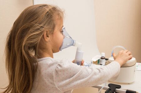 Close up. Respiratory diseases. A 5-year-old child turns on a button on the nebulizer to begin...
