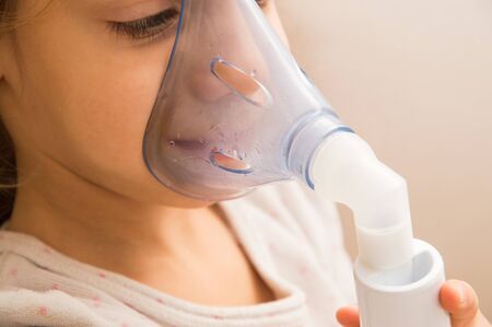Close up, macro. Respiratory diseases. The child's face in the process of inhalation with a nebulizer. Clinic, treatment. Therapy of coronavirus, broncho tracheitis, asthma.の写真素材