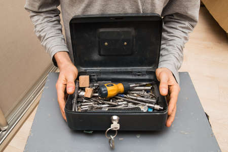 Close up. Home renovation tool kit, furniture setting. Male hands are holding an open toolbox.